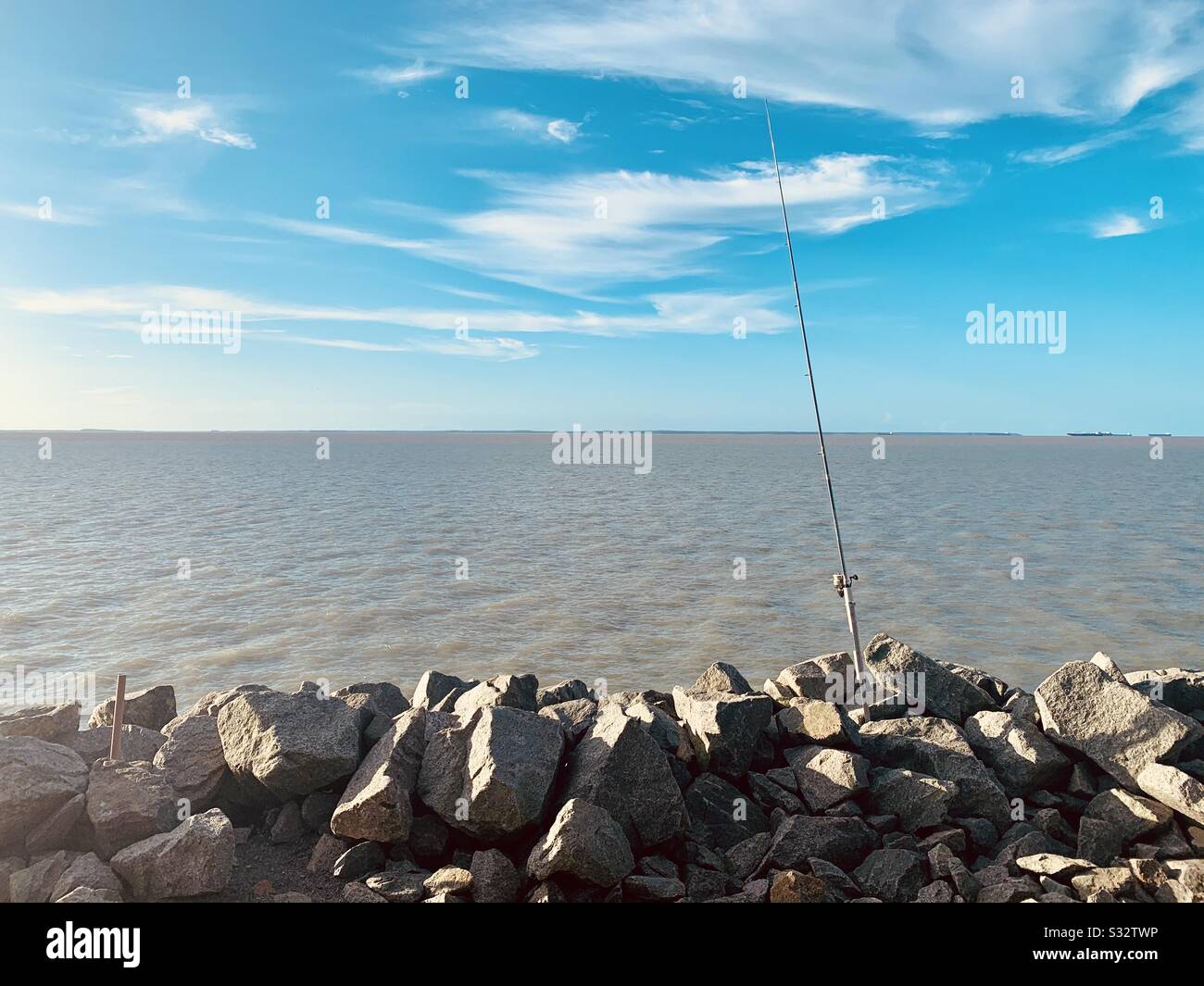 Ciel, mer, rochers et canne à pêche. Banque D'Images