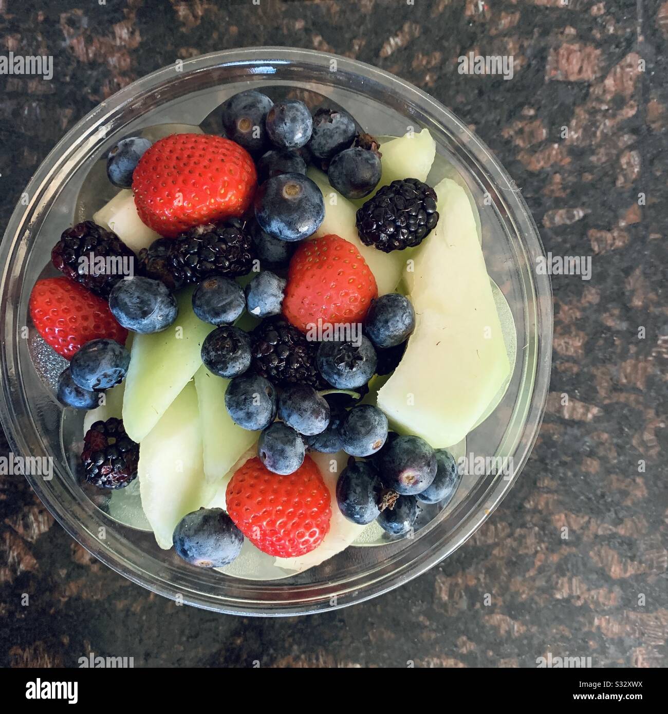 Un bol de fruits frais sains et délicieux, de miel, de fraises, de bleuets et de framboises. Banque D'Images
