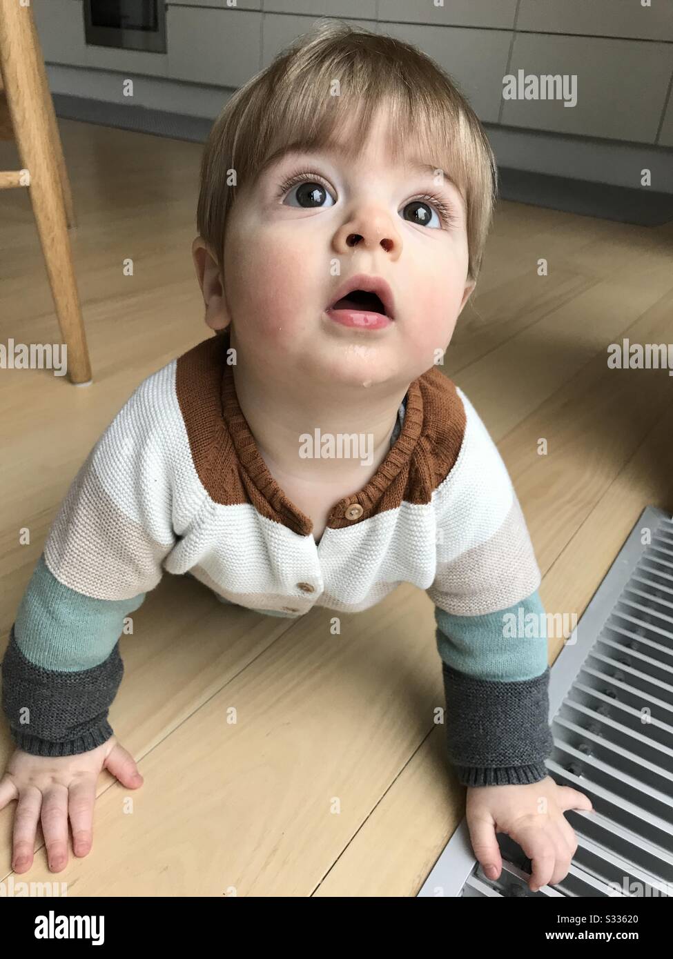 Beau Garcon De Bebe Rampant Sur Un Plancher En Bois Et Regardant Vers Le Haut Avec De Grands Yeux Photo Stock Alamy
