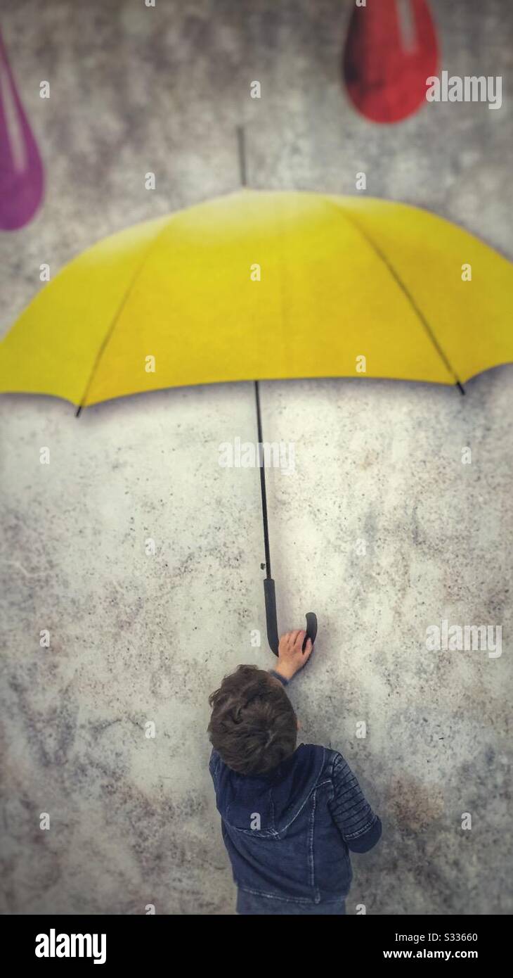 Très petit portant un parapluie jaune peint Banque D'Images