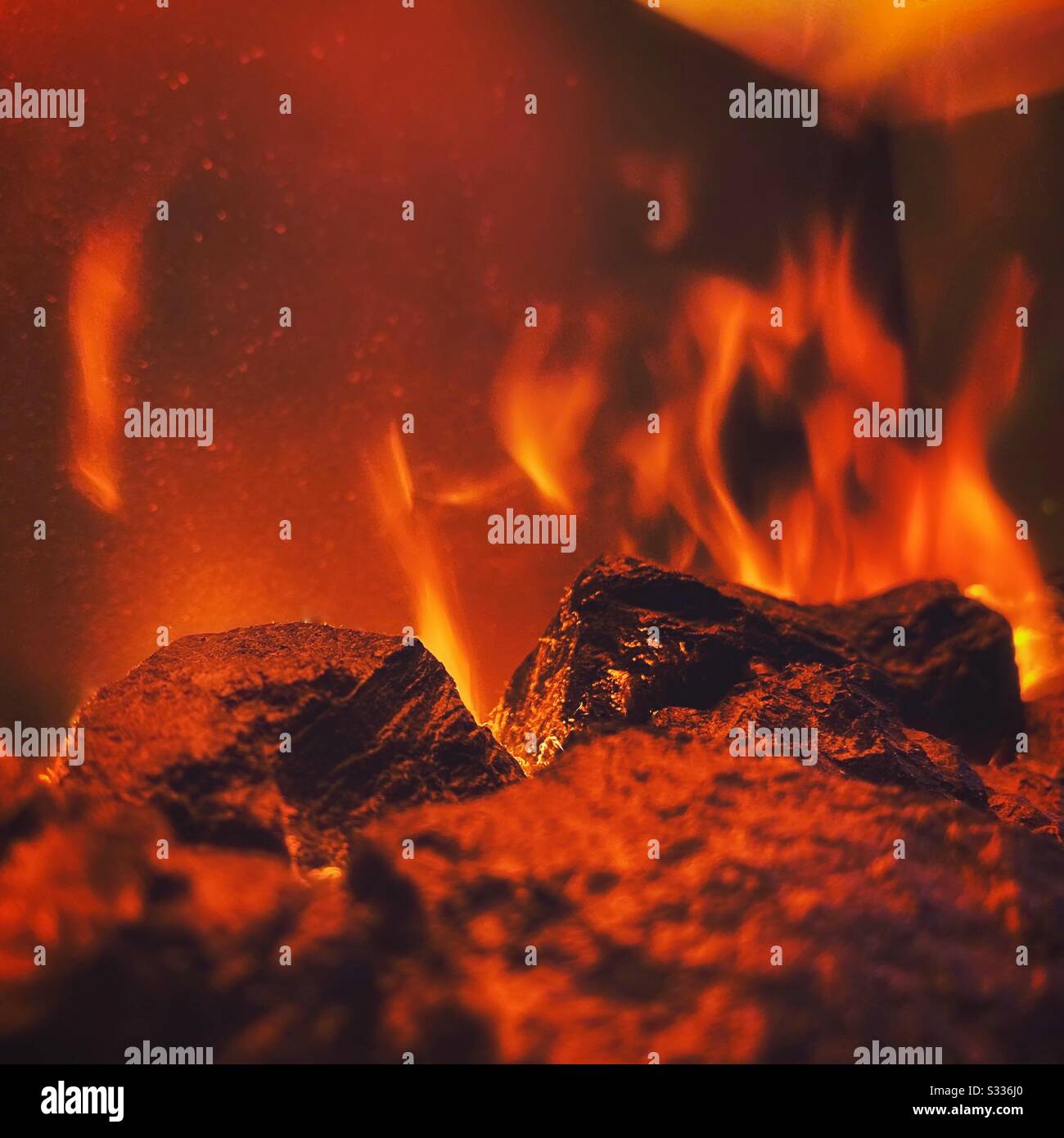 Vue rapprochée des coals chauds dans une cheminée avec des flammes chaudes orange et rouges et un espace de copie. Concept de passion intense - Image de stock capturée avec un smartphone