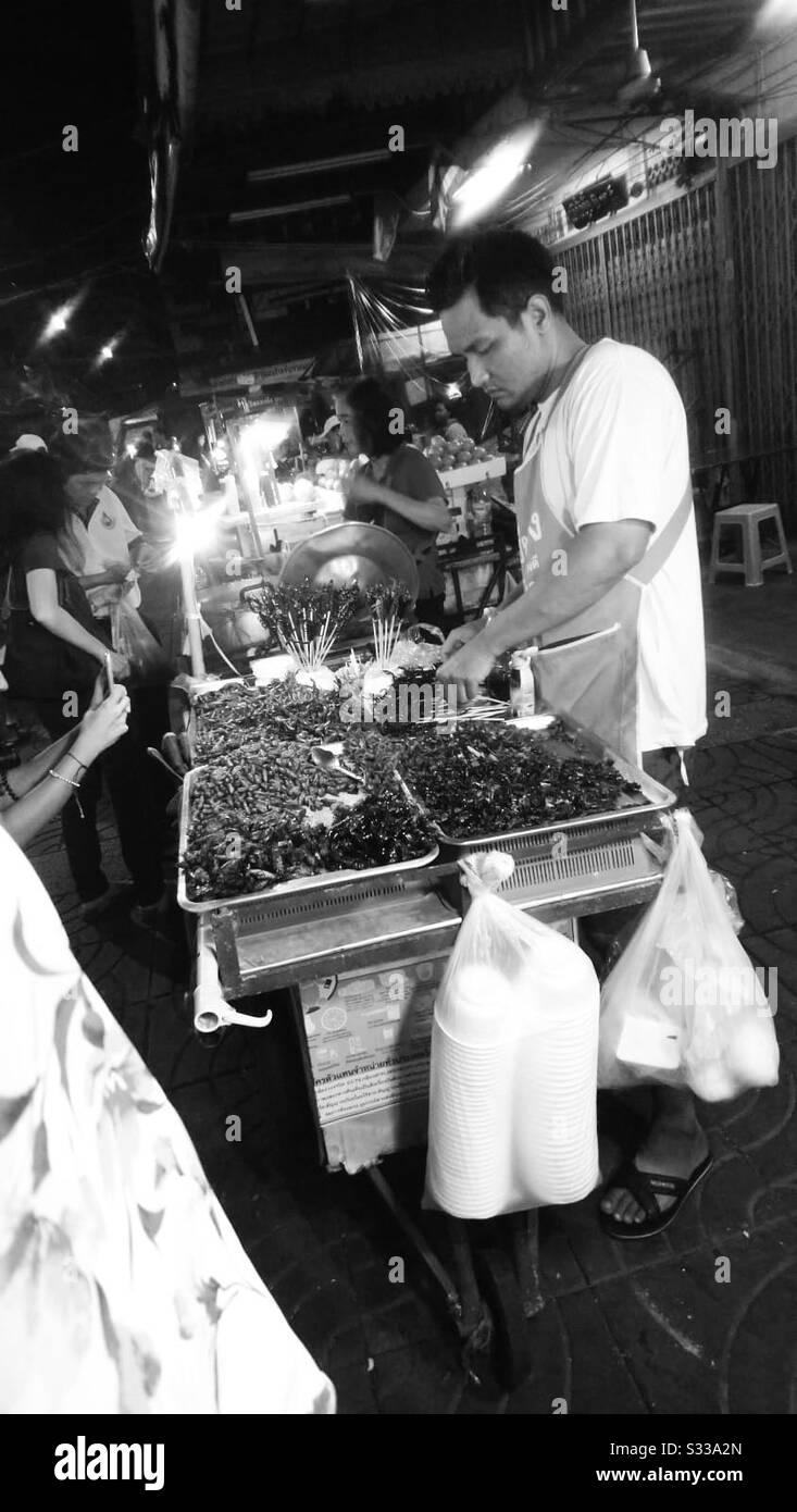 Vendeur de rue vendant la délicatesse scorpienne en Asie la nuit en noir et blanc Banque D'Images