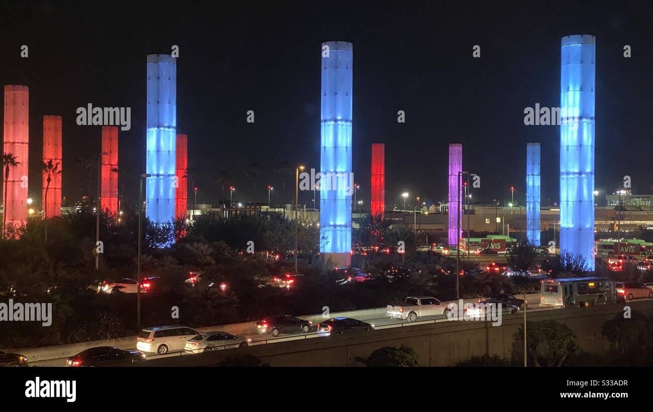 Los ANGELES, CA, JAN 2020: L'installation de la colonne lumineuse brille dans les tons de bleu et de rouge la nuit, avec le trafic passant en premier plan à l'extérieur de l'aéroport international de Los Angeles Banque D'Images