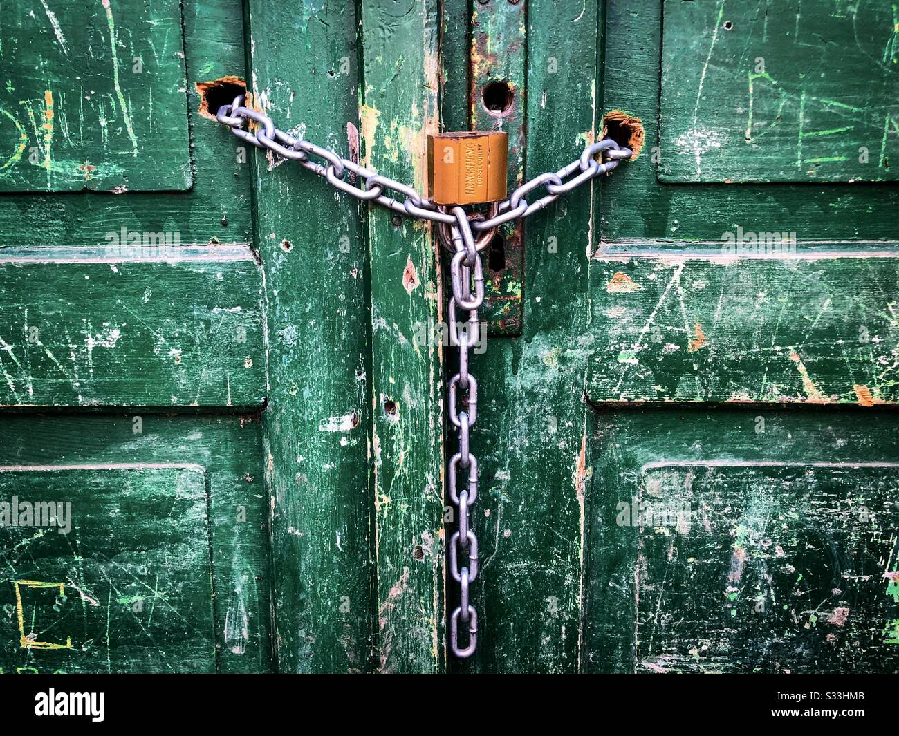 Cadenas doré avec chaîne sur une porte en bois verte Banque D'Images