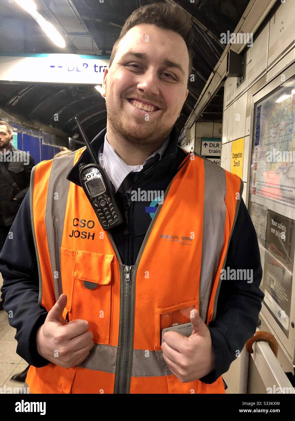 Homme travailleur souterrain de Londres souriant portant un gilet de sécurité aidant les travailleurs de la navette Banque D'Images