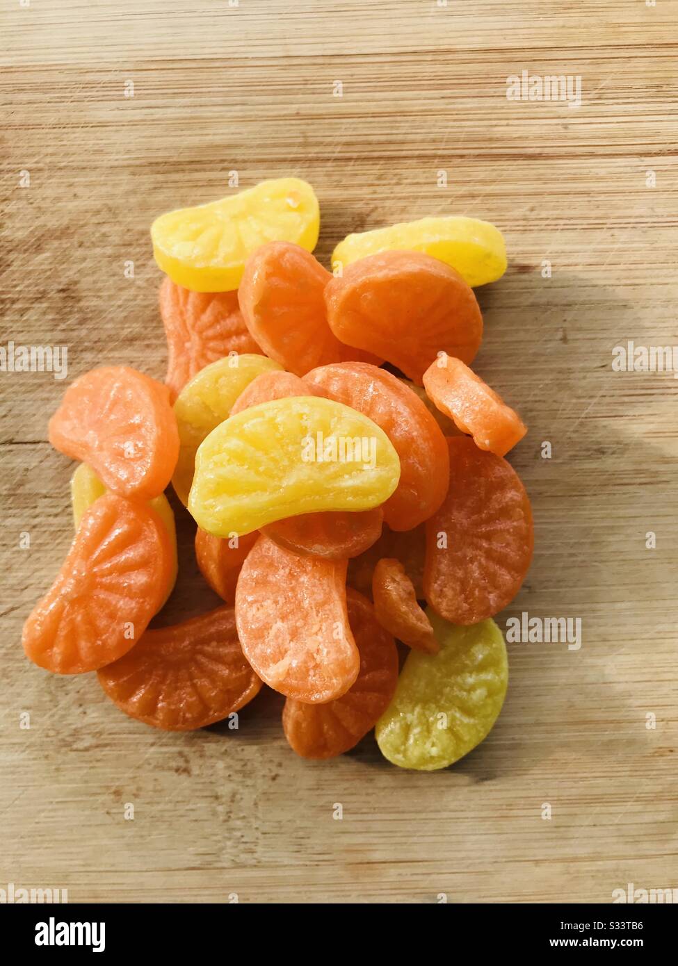 Bonbons aux agrumes - Naranga mittai- bonbons à sucre de couleur orange et  jaune-achetés à l'épicerie fond planche en bois- mode de changement de  couleur- gros plan des bonbons à la marmalade