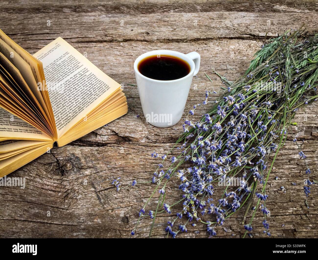 Tasse de café, un livre et des fleurs de lavande sur une table rustique en bois Banque D'Images
