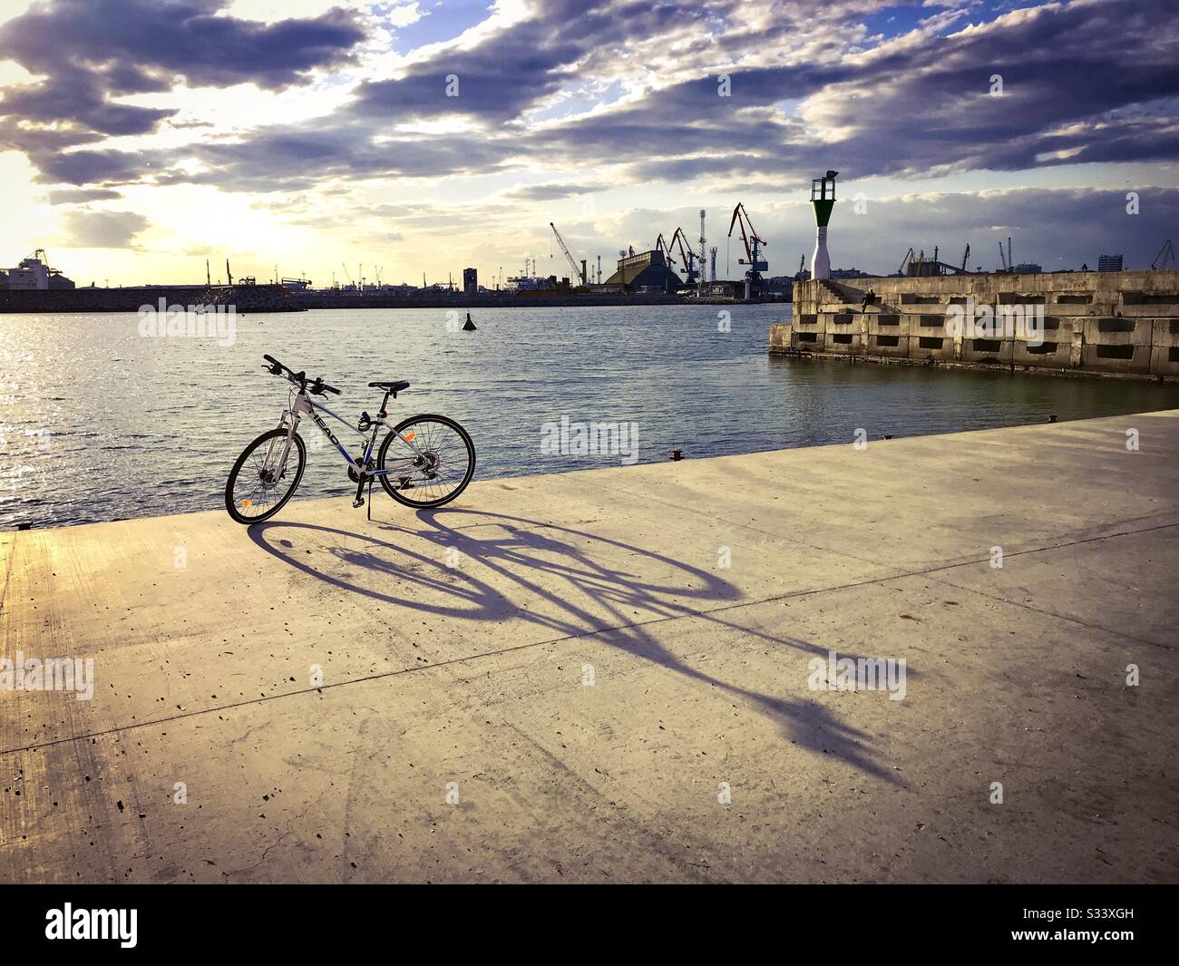 Port industriel de la mer Noire de Burgas, Bulgarie. Vélo bleu et blanc de LA COMPAGNIE DE TÊTE garée près de la mer. - Image de stock capturée avec un smartphone