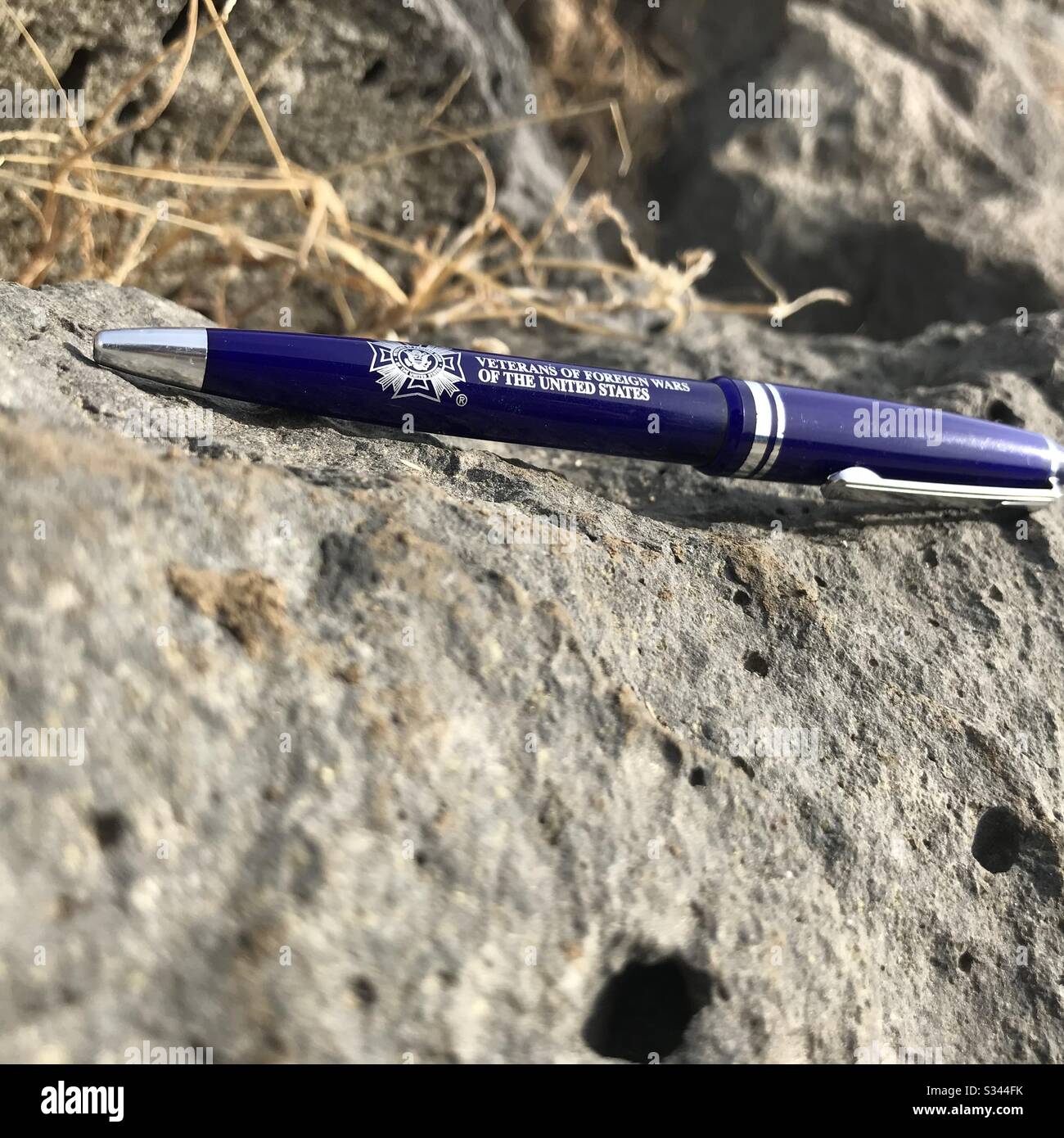 Cette photo montre un stylo avec une inscription qui dit "anciens combattants des guerres étrangères des États-Unis" qui est dans une surface rocheuse. Vous pouvez également voir le soleil brille dans le stylo. Banque D'Images