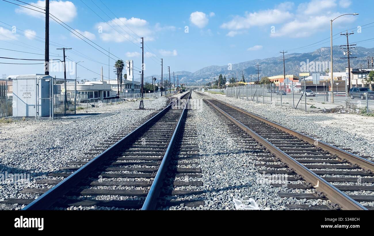 GLENDALE, CA, FÉVRIER 2020: Voies ferrées en direction de montagnes lointaines, ciel bleu avec nuages clairsemés Banque D'Images