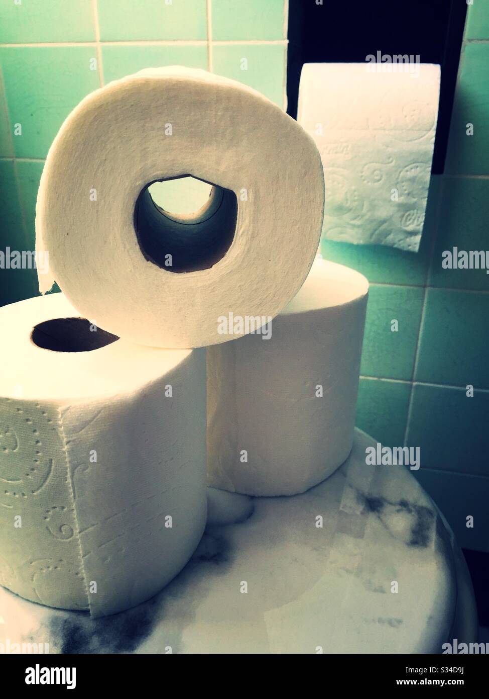 Rouleaux de papier toilette empilés sur un couvercle de toilettes dans une salle de bains résidentielle, États-Unis Banque D'Images