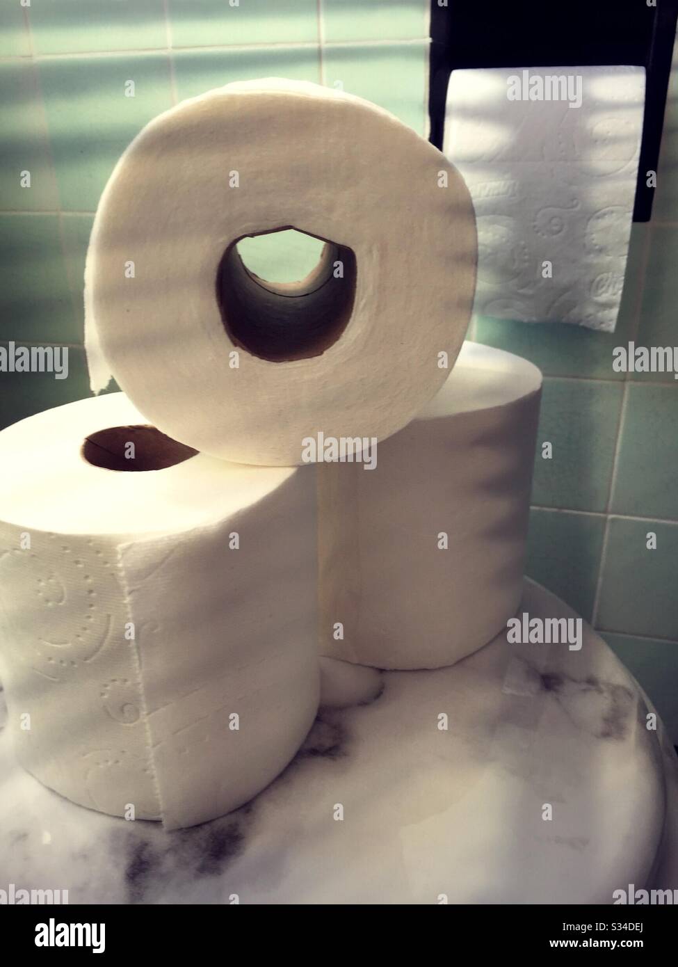 Rouleaux de papier toilette empilés sur un couvercle de toilettes dans une salle de bains résidentielle, États-Unis - Image de stock capturée avec un smartphone