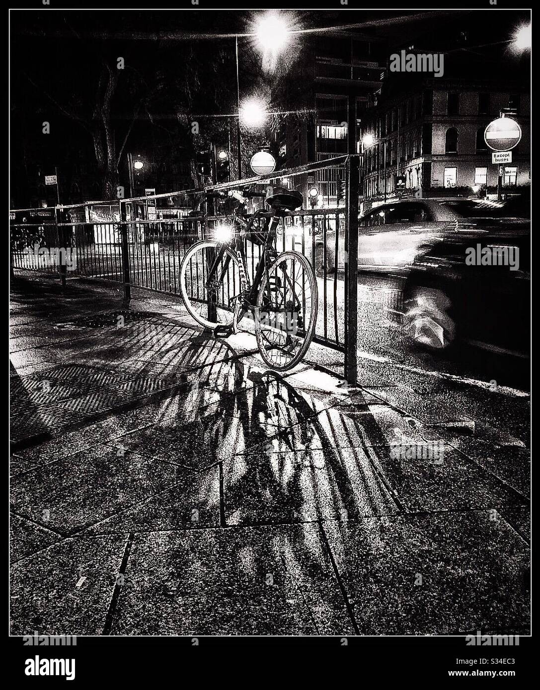 Un vélo est enchaîné à des chemins de fer la nuit à Londres. Banque D'Images