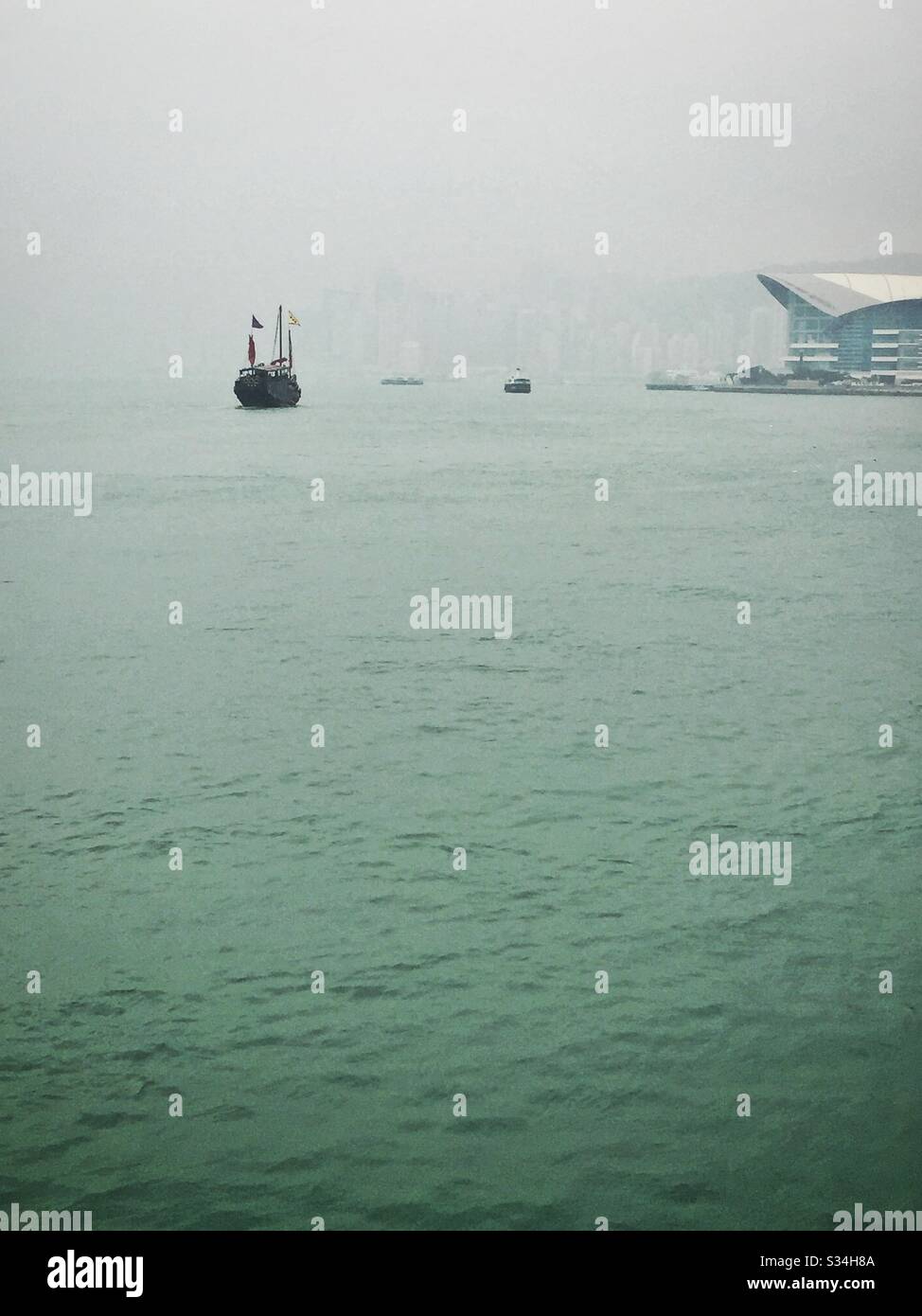 Le 'Aqua Luna', une réplique de la jonque chinoise utilisée pour les visites touristiques, sur le port de Victoria, une journée hazy à Hong Kong Banque D'Images