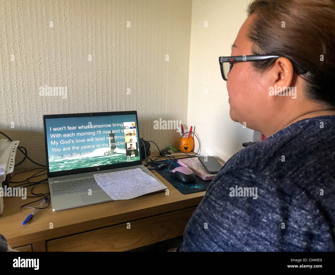 Une dame participe à un service d'église de la maison par vidéoconférence en raison de la pandémie de Coronavirus. - Image de stock capturée avec un smartphone