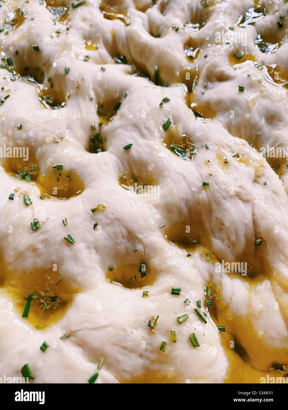 Gros plan sur la pâte à pain focaccia maison - avec de l'huile d'olive, du romarin et du sel de mer - sur le point d'être cuit au four. Banque D'Images