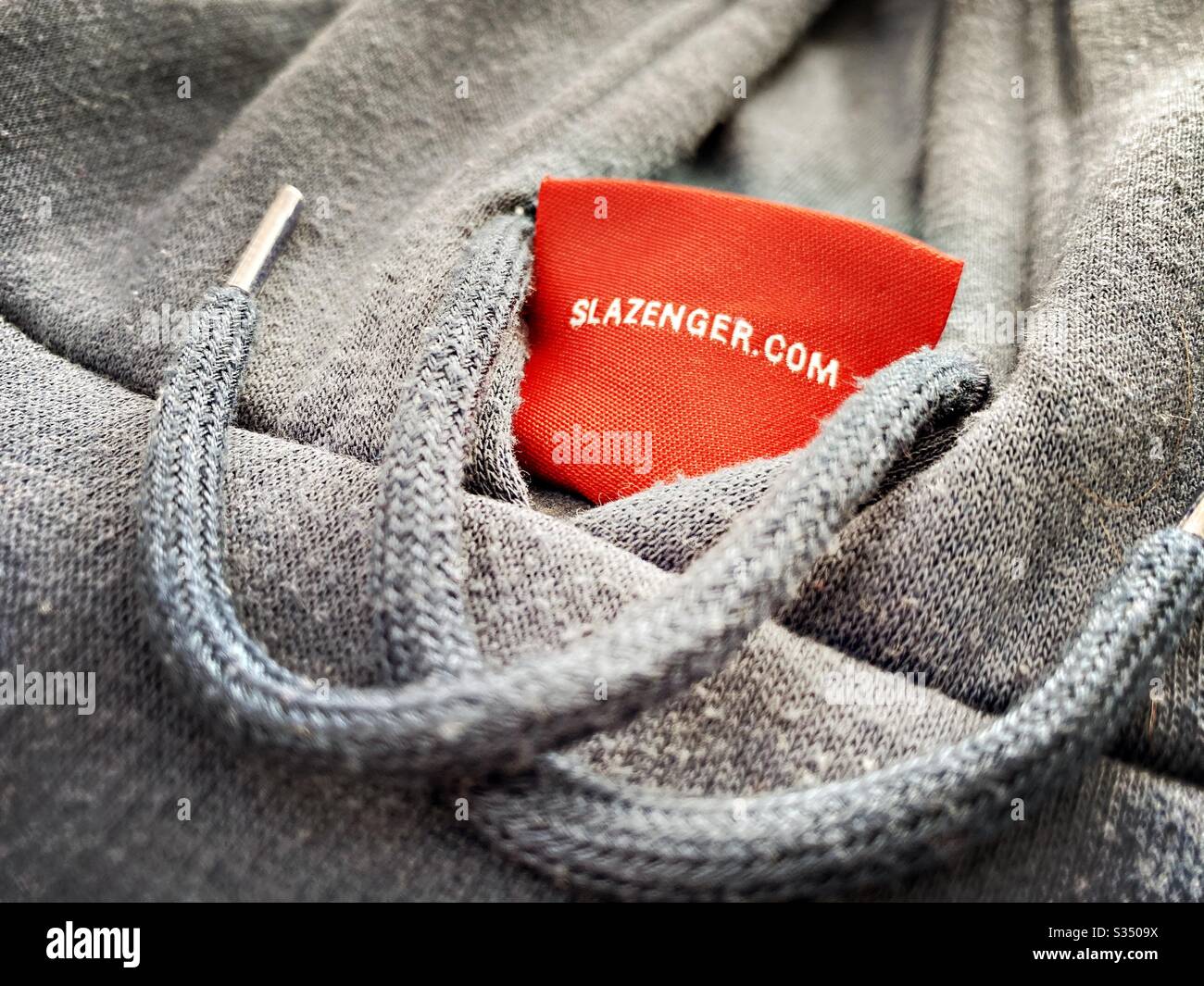 Gros plan sur les vêtements de designer pour hommes, vêtements pour hommes. Étiquette rouge sur un haut à capuche Slazenger, à capuche et à capuche. - Image de stock capturée avec un smartphone