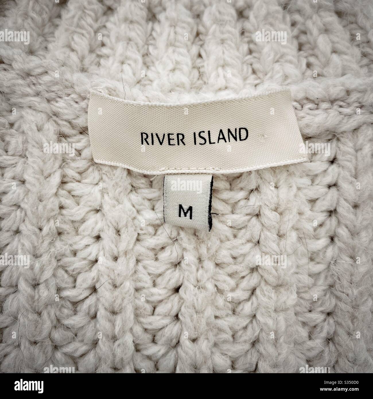Gros plan sur les vêtements de designer pour hommes, vêtements pour hommes. Etiquette de taille moyenne de River Island sur un pull à grosse maille. - Image de stock capturée avec un smartphone