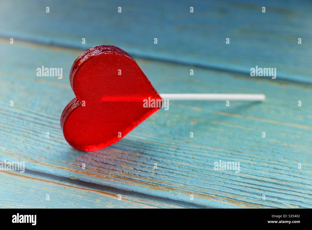 Rouge coeur lollipop sur table en bois bleu Banque D'Images