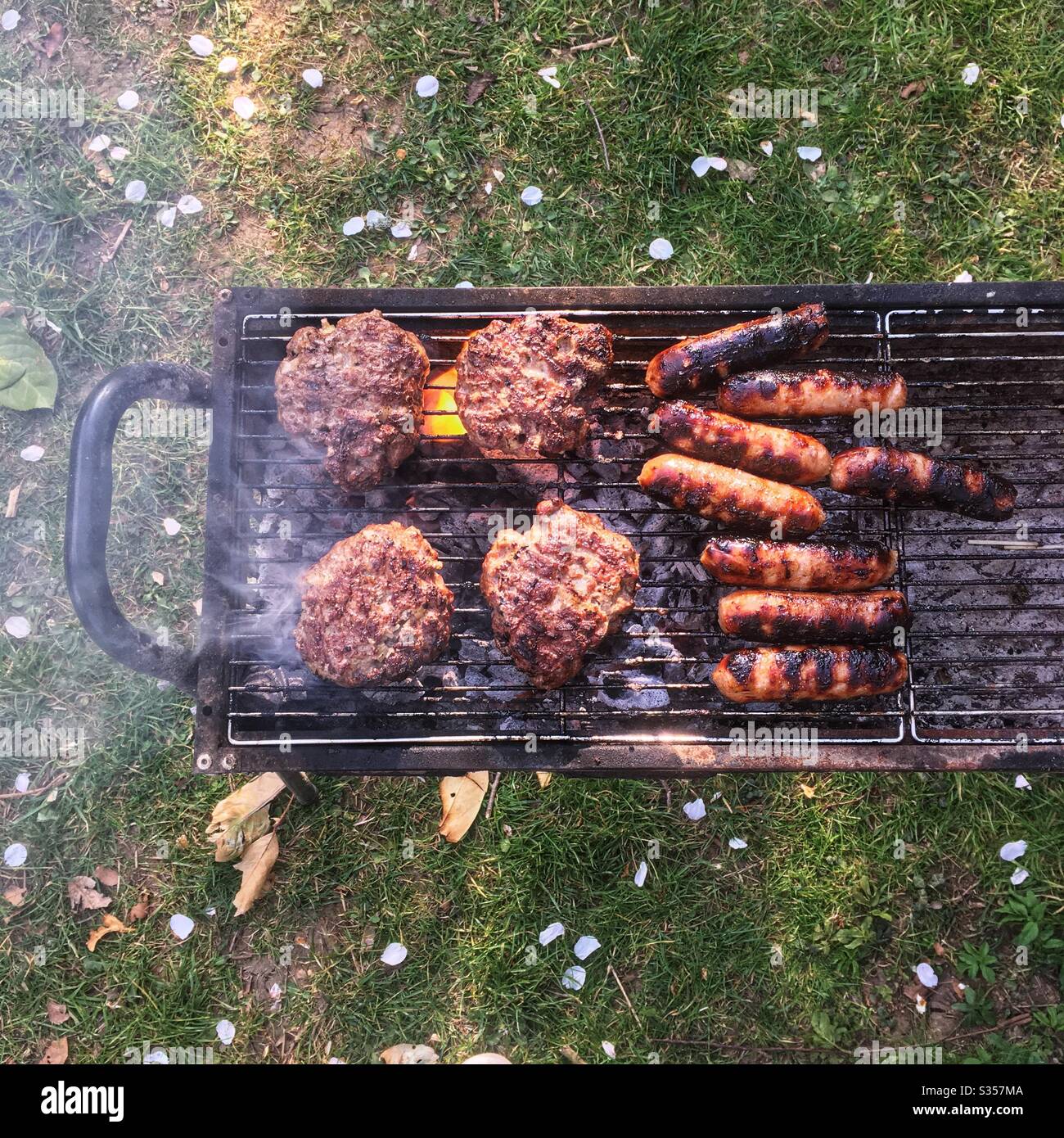 Barbecue au charbon de bois, hamburgers et saucisses, Hampshire, Angleterre, Royaume-Uni. - Image de stock capturée avec un smartphone