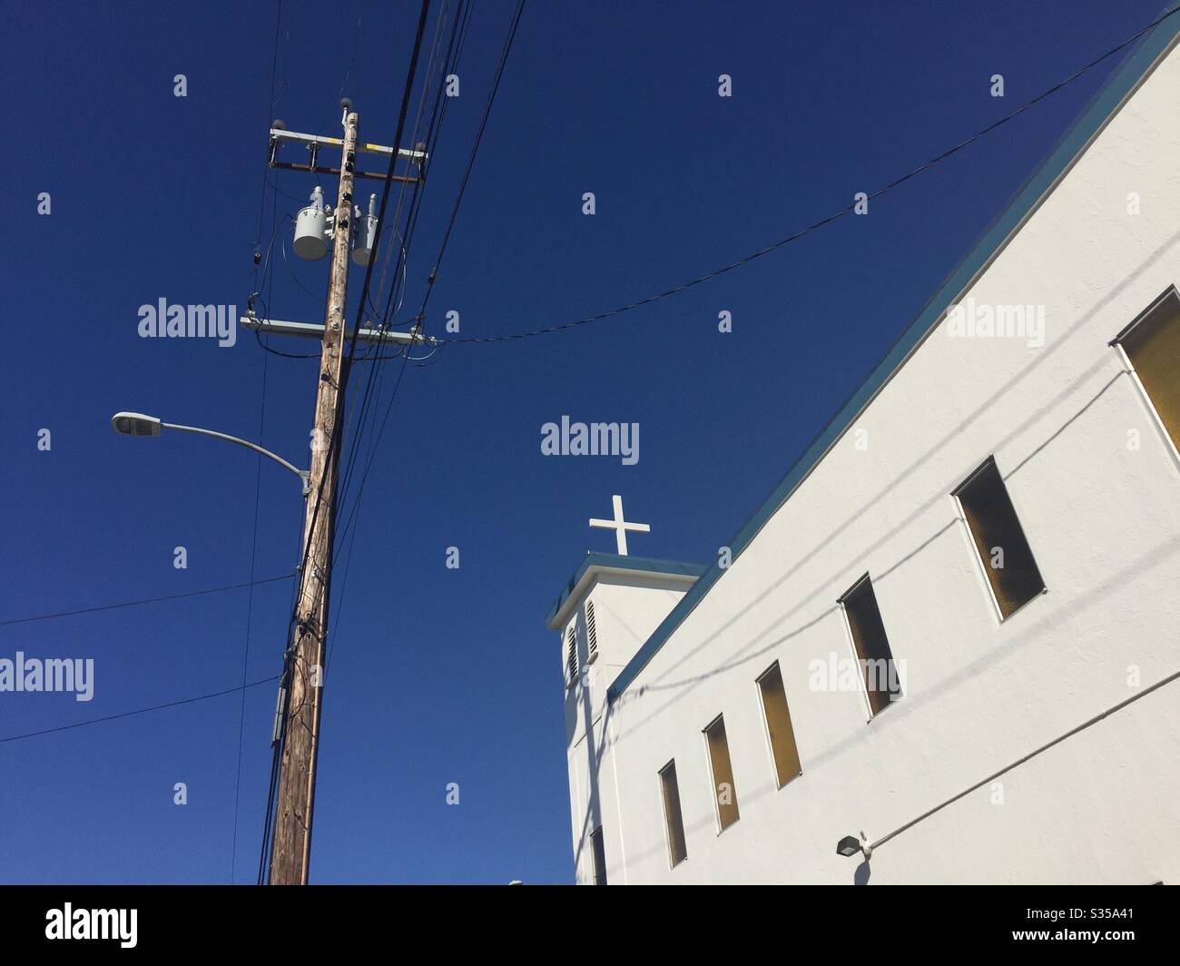 Joshua Christian Church sur Grand Avenue. Croix blanche avec poteau téléphonique et borne lumineuse contre un ciel bleu. West Oakland, Californie. - Image de stock capturée avec un smartphone
