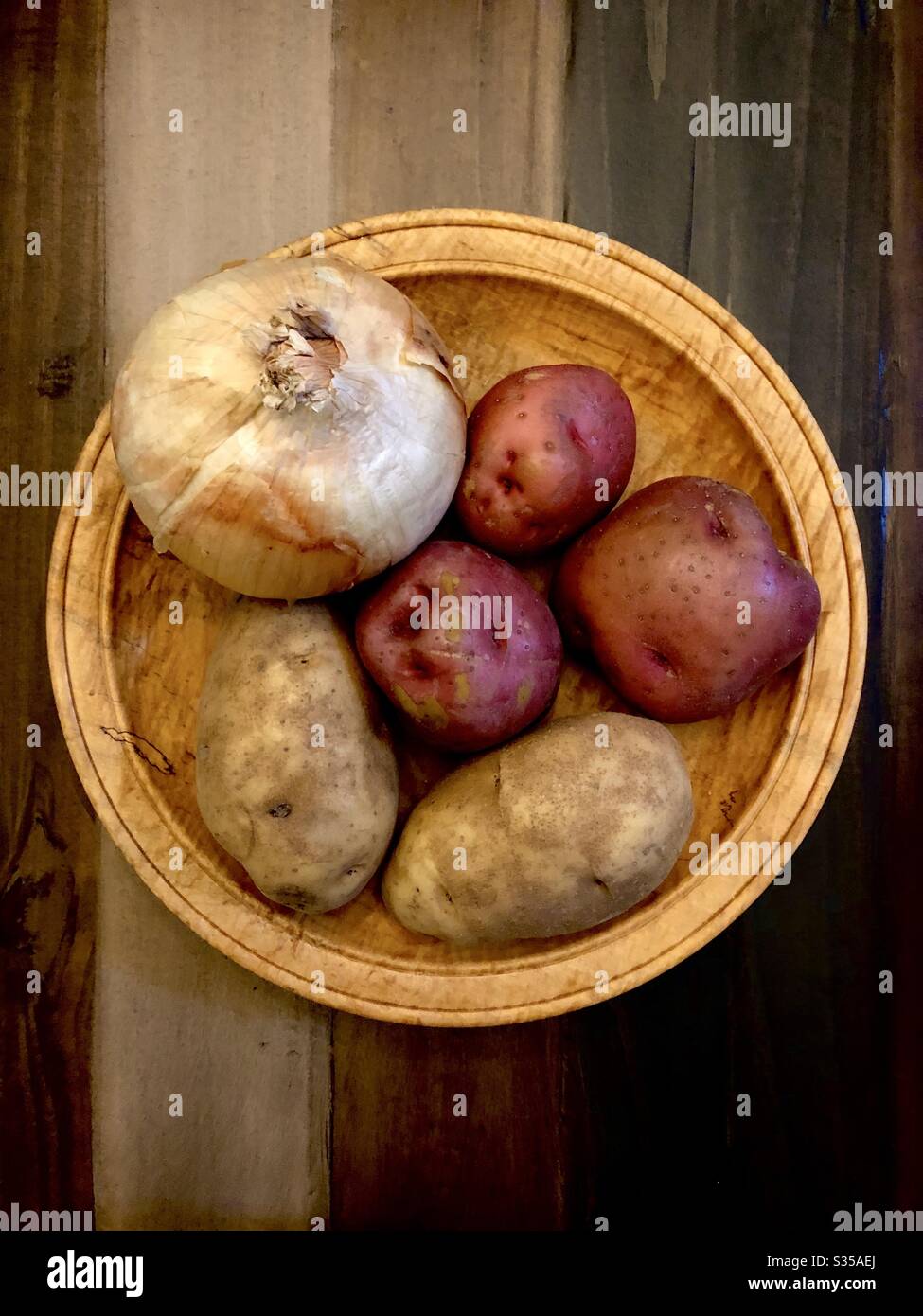 Toujours la vie d'un oignon et de cinq pommes de terre dans un bol en bois. Banque D'Images