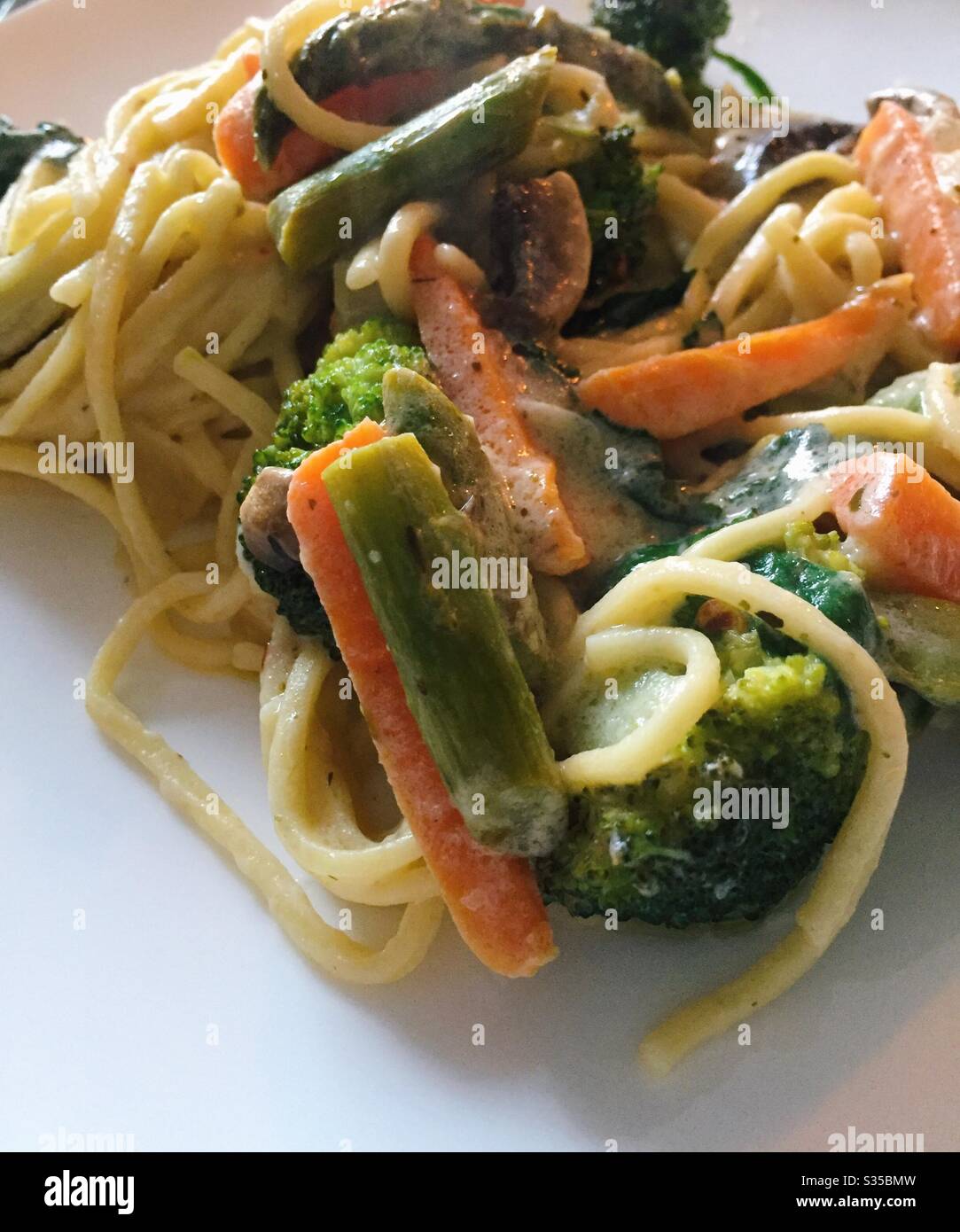 Gros plan sur un plat appétissant de pâtes Primavera sur une assiette blanche de chine - Image de stock capturée avec un smartphone