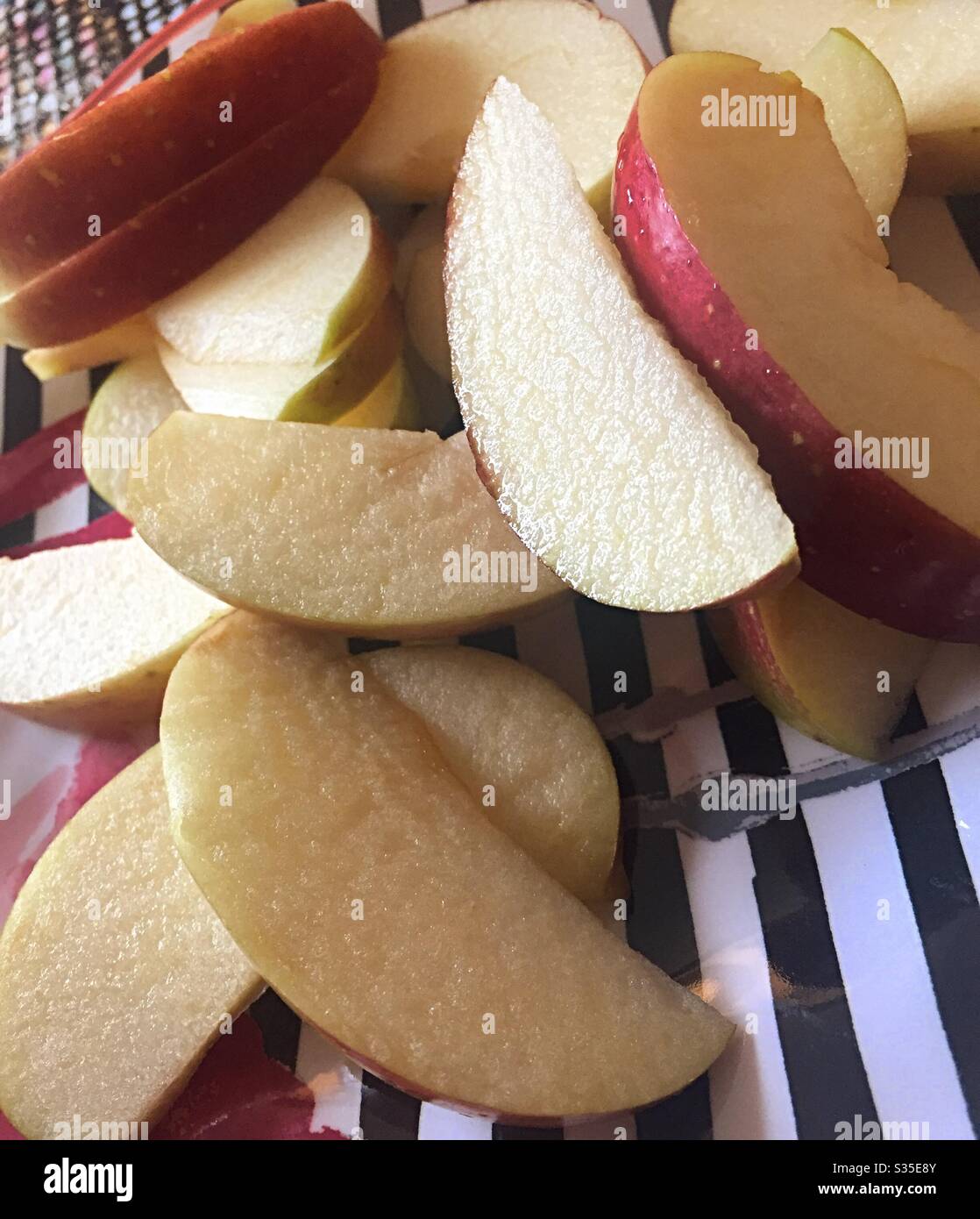 Tranches de la pomme Fuji fraîche sur une plaque rayée noire et blanche - Image de stock capturée avec un smartphone