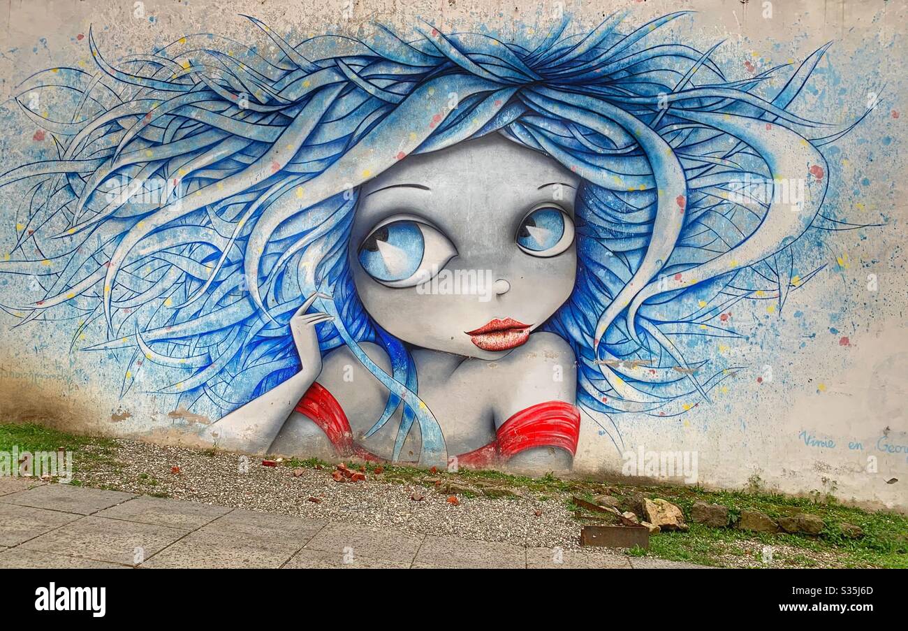 Street art d'une fille avec des yeux énormes, cheveux bleus et un sommet rouge. Kutaisi, Géorgie. Banque D'Images