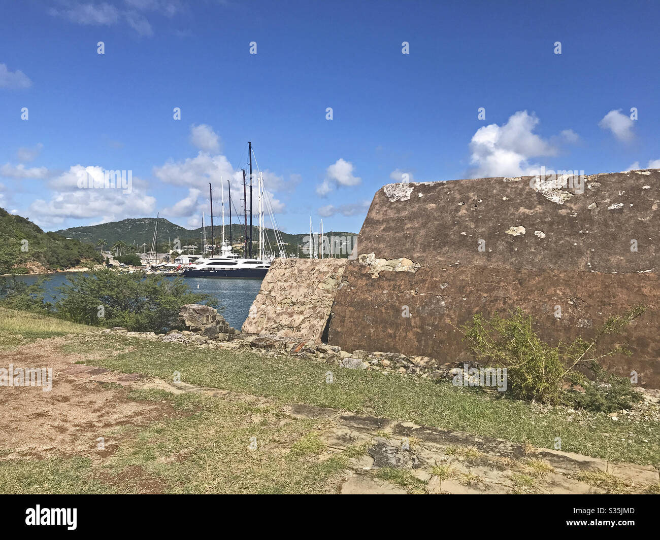 Poudrage Magazine à fort Berkeley en Antigua-et-Barbuda, Caraïbes, Petites Antilles, Antilles avec English Harbour en arrière-plan et ciel bleu copier l'espace. Banque D'Images