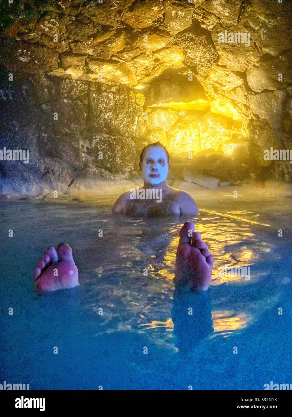 Homme portant un masque de silice flottant dans une grotte aquatique. Lagon bleu, Islande. - Image de stock capturée avec un smartphone