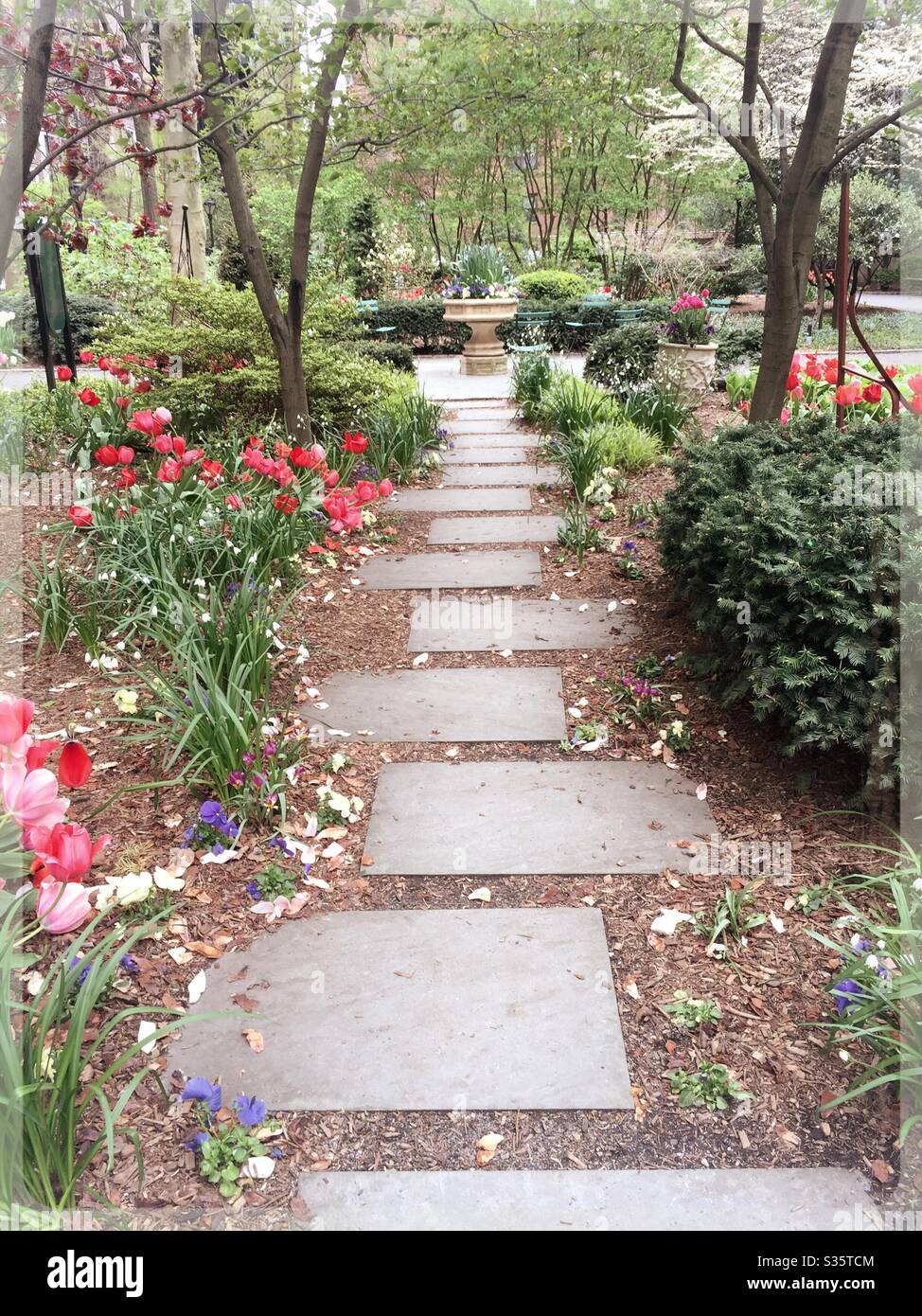 Une passerelle en pierre de voûte dans les greens de la ville de Tudor mène à un bain d'oiseaux en pierre, NYC, USA Banque D'Images