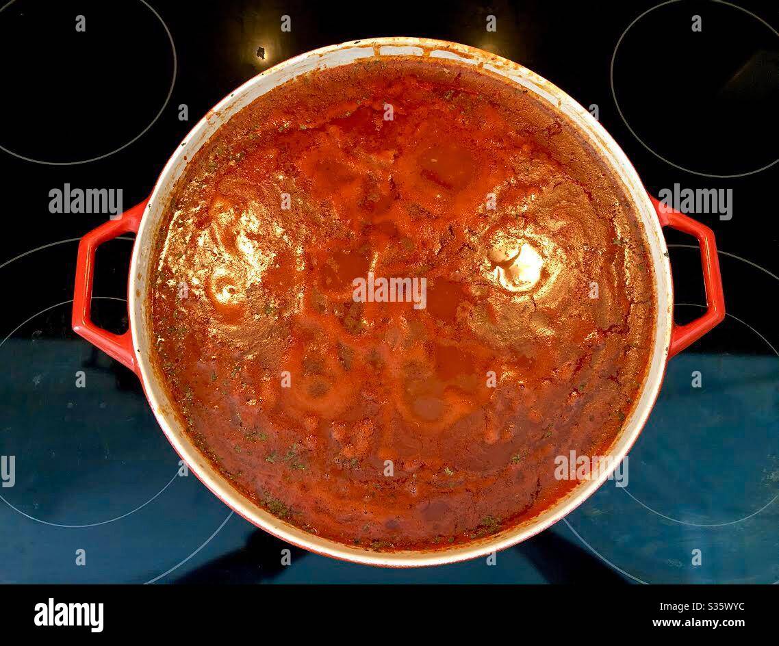 Vue d'ensemble d'une grande casserole de cuisine maison de sauce rouge sur le poêle. - Image de stock capturée avec un smartphone