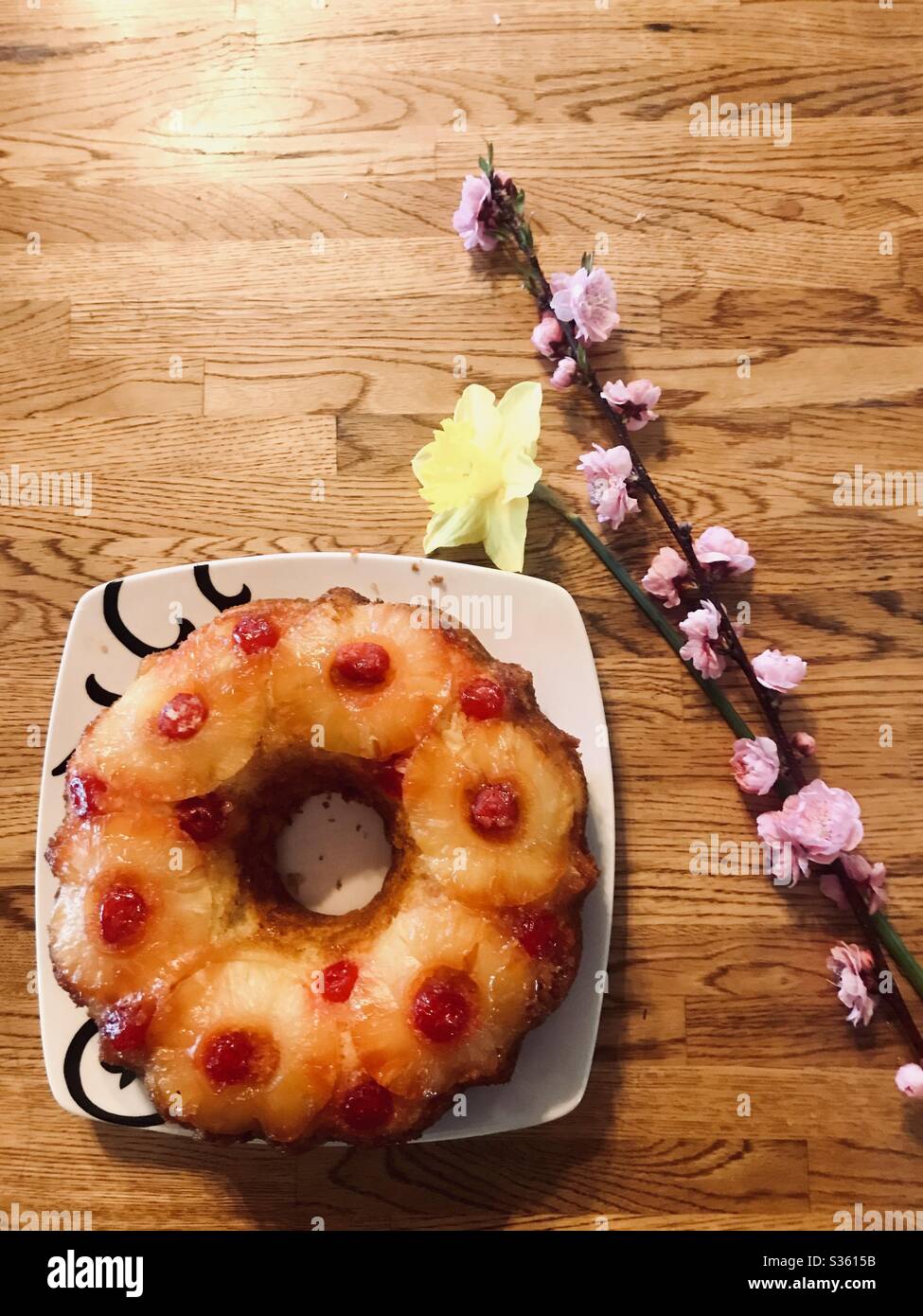 Un Gateau A L Envers A L Ananas Sur Une Assiette Sur Une Table Avec Une Branche De Fleurs De Pomme Et Une Fleur De Jonquille Photo Stock Alamy