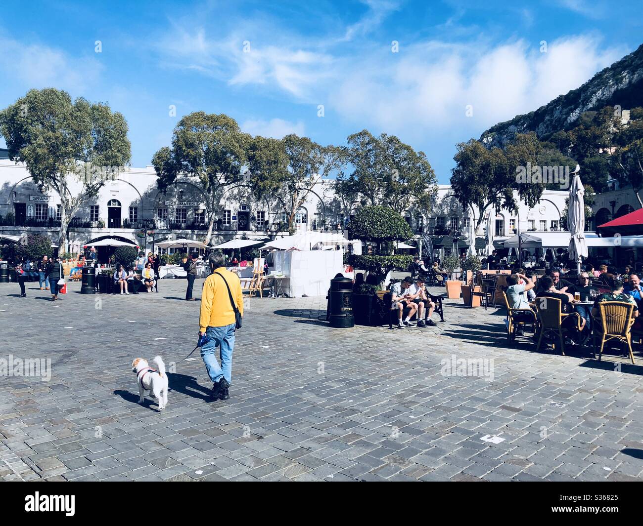 Homme marchant son chien à travers la place Casemates à Gibraltar Banque D'Images