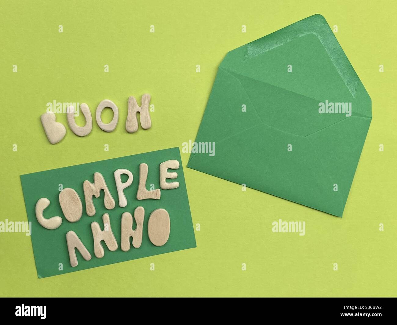 Buon Compléno, texte italien signifiant Joyeux anniversaire composé de lettres en bois faites à la main sur la couleur verte - Image de stock capturée avec un smartphone