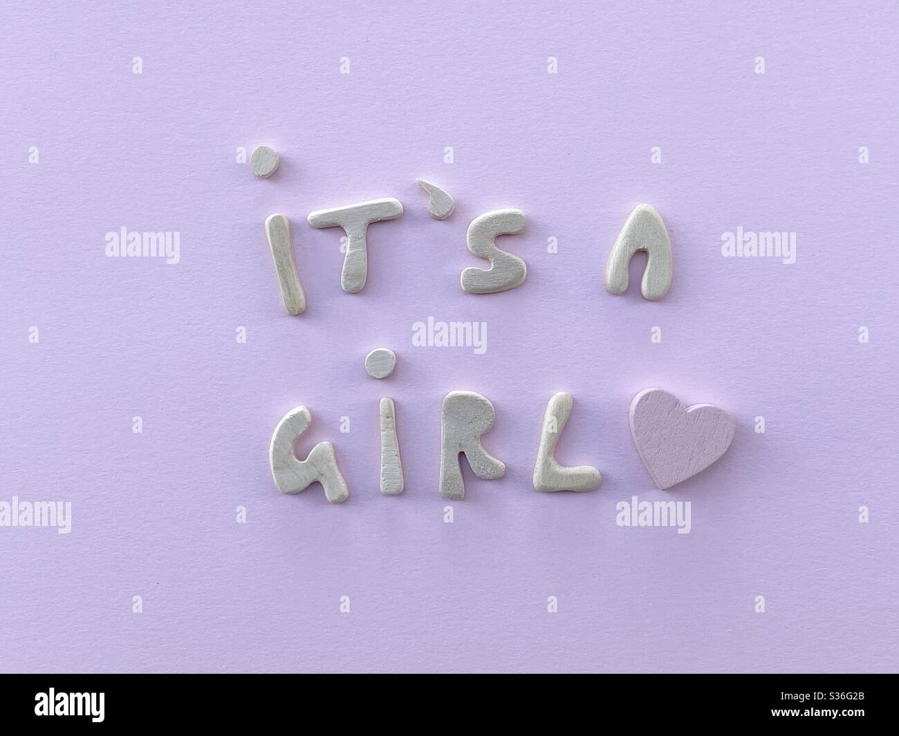 C’est un message de fille avec un coeur en bois rose composé de lettres en bois faites à la main sur fond rose - Image de stock capturée avec un smartphone