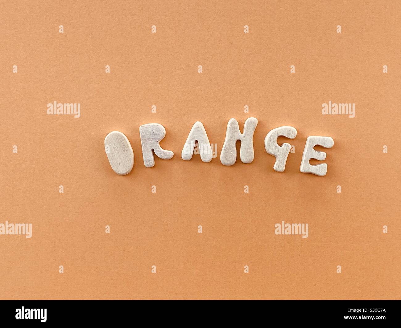 Mot orange composé de lettres en bois faites à la main sur une couleur orange - Image de stock capturée avec un smartphone