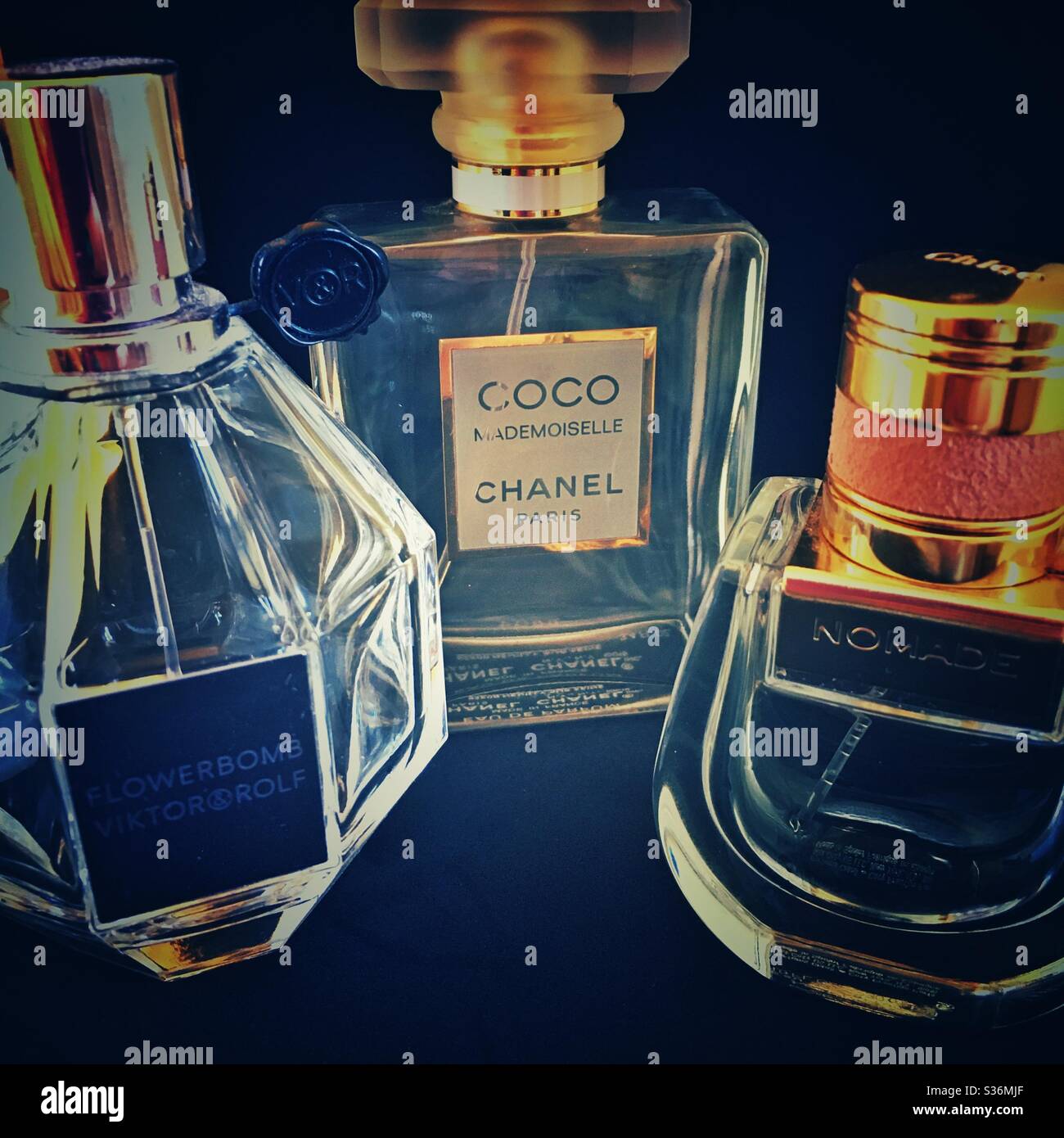 Une photographie de trois flacons de parfum, marques haut de gamme de créateurs. Chanel, Chloe et Viktor & Rolf. Parfums coco Mademoiselle, Nomade et Flowerbomb. Arrière-plan noir. Banque D'Images