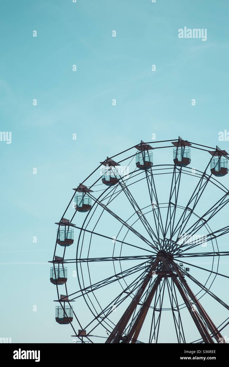 Une grande roue ronde à une foire amusante dans un ciel bleu clair Banque D'Images