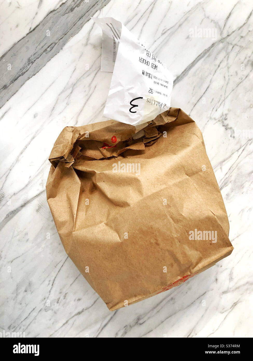 Sac de plats à emporter sur un comptoir en marbre dans la cuisine à la maison, à partir d'une commande en ligne et de ramassage sans contact Banque D'Images