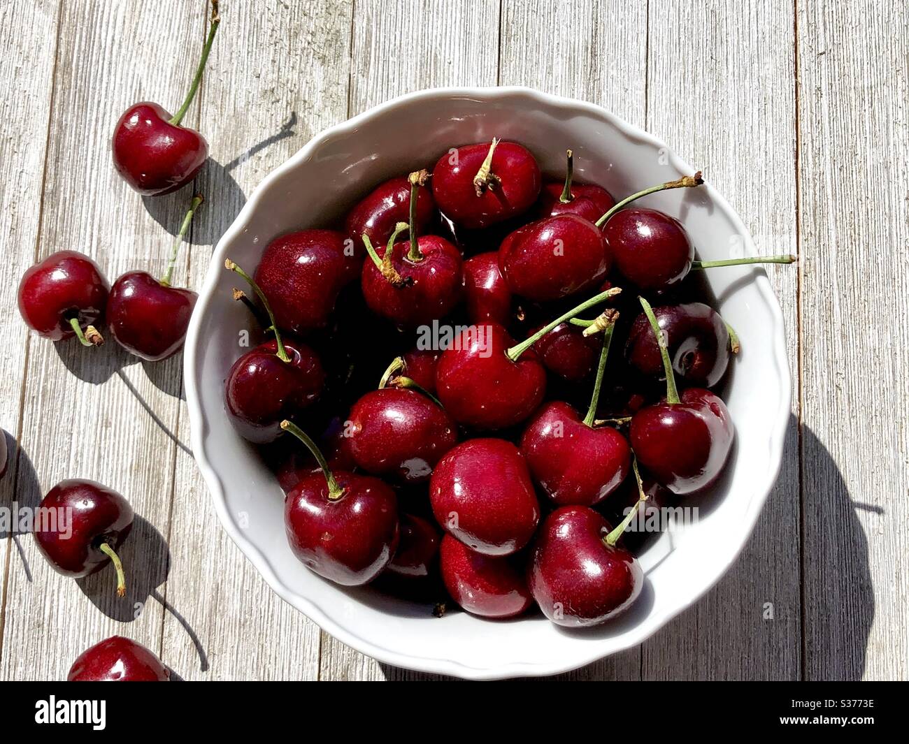 Cerises douces dans un bol blanc sur une table en bois Banque D'Images
