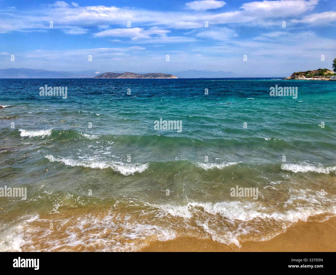 Vue sur les vagues avec mousse blanche et petite île de Thasopoula depuis l'île de Thassos en Grèce. Banque D'Images