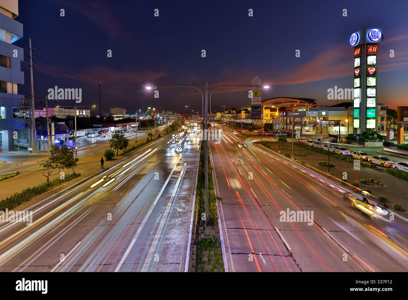 Iloilo City, Philippines- 12 mai 2020 : circulation le soir le long d'une autoroute très fréquentée. Traînées de lumière de voiture à exposition longue. Banque D'Images
