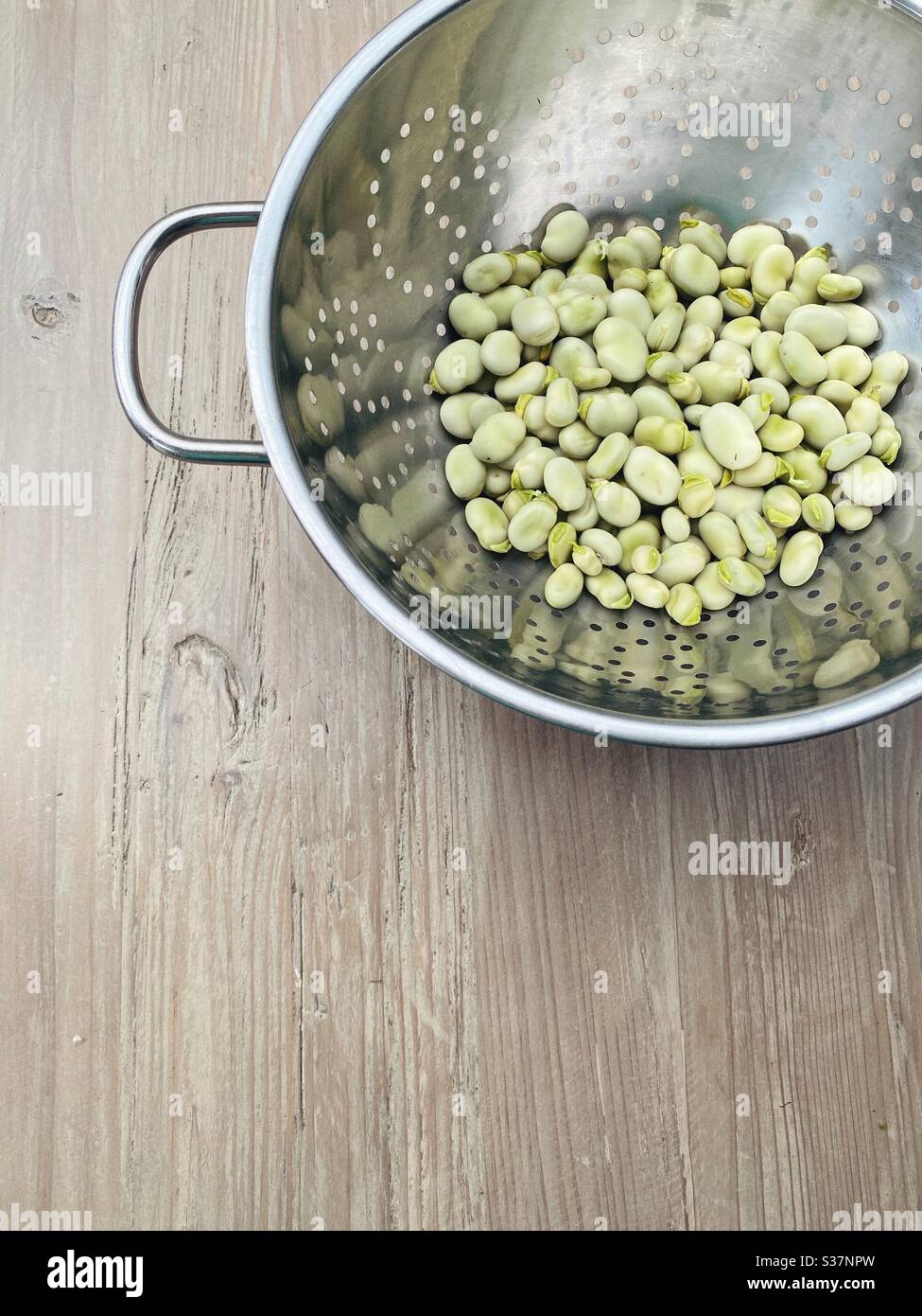 Fèves fraîchement podées dans une passoire en métal, perspective platlay, demi cadre, espace vierge, d'en haut, rustique, minimal - Image de stock capturée avec un smartphone