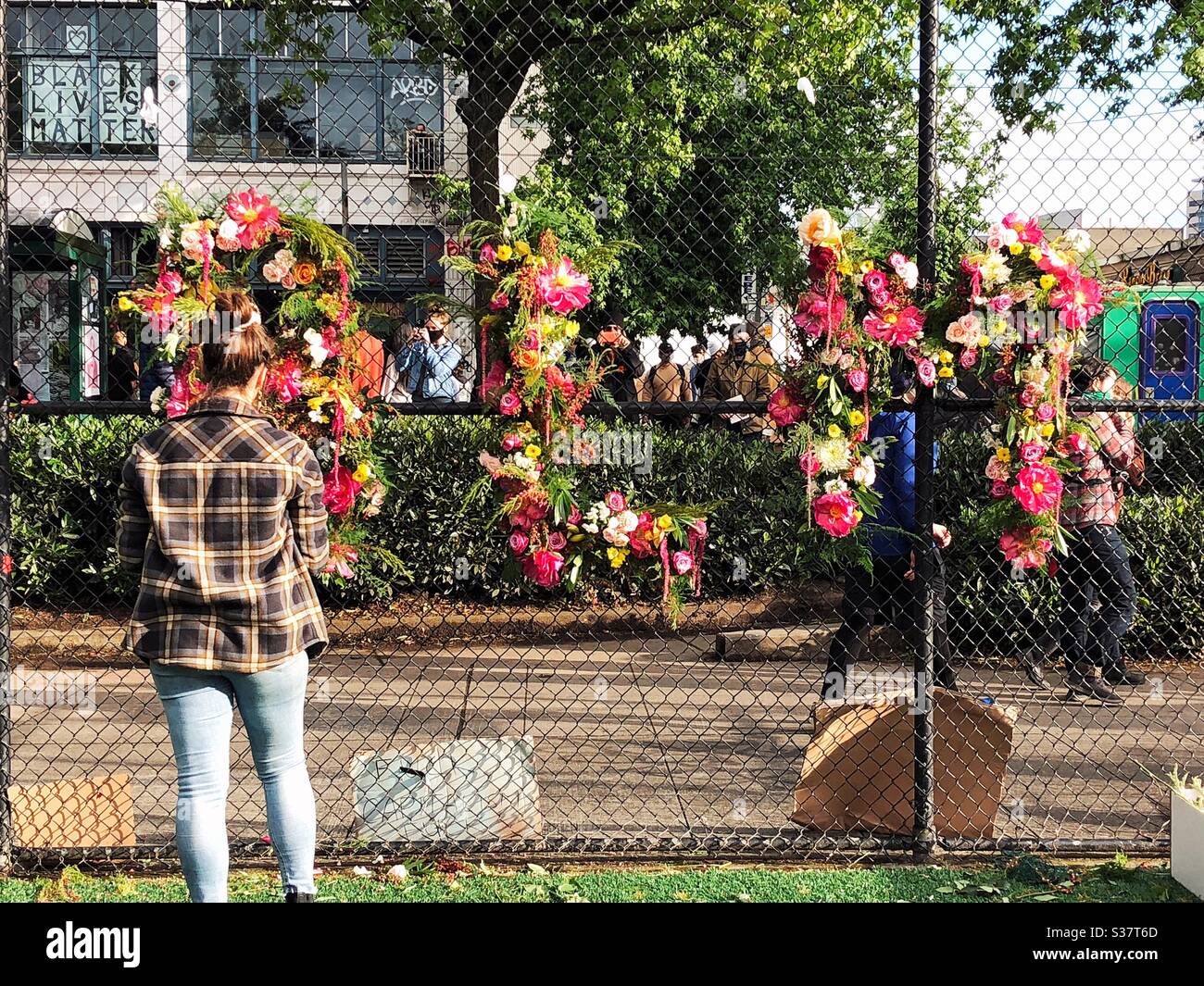 Femme crée le signe BLM à partir de fleurs fraîches sur une clôture à Seattle près DE CHOP zone autonome CHAZ Banque D'Images