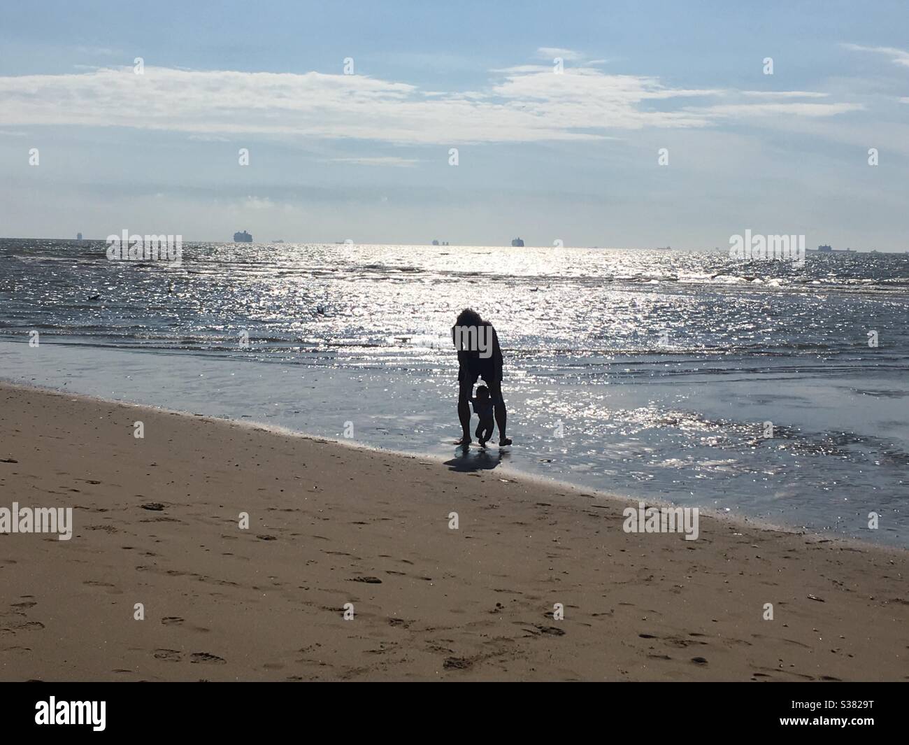 Un bébé est tenu par son père alors qu'il marche dans la mer du Nord sur une plage à Katwijk, aux pays-Bas Banque D'Images