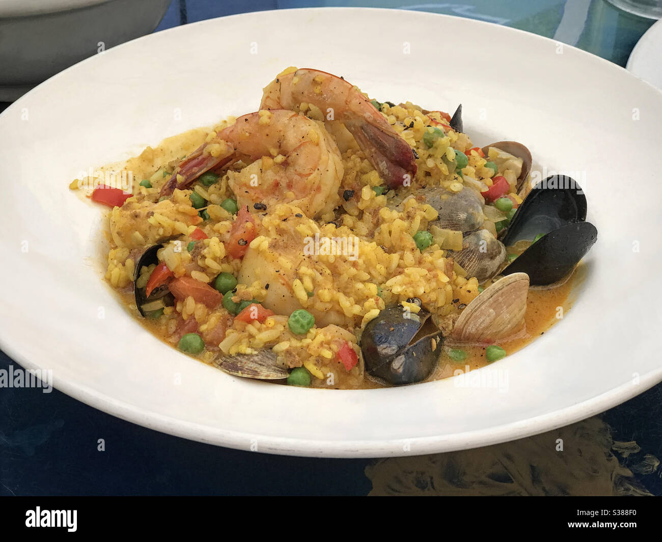 Un plat de paella, composé de crevettes, de moules, de palourdes, de pétoncles et de riz au safran dans un bouillon de fruits de mer, est présenté dans un restaurant avec vue rapprochée. Banque D'Images