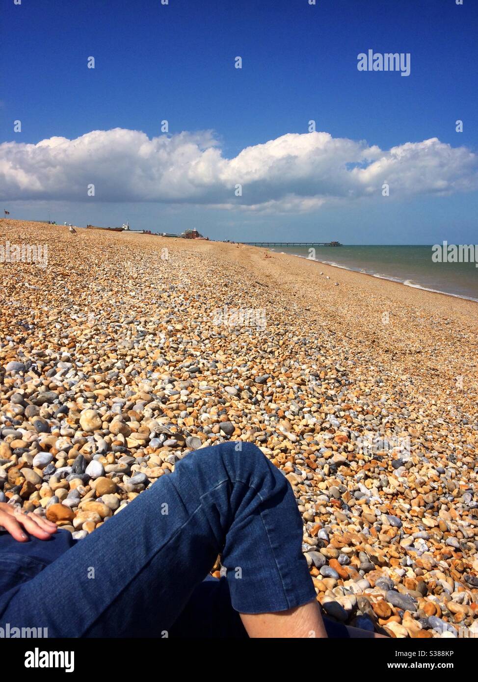 Femme allongé sur la plage portant un Jean avec la jetée en arrière-plan à Deal Kent UK Banque D'Images
