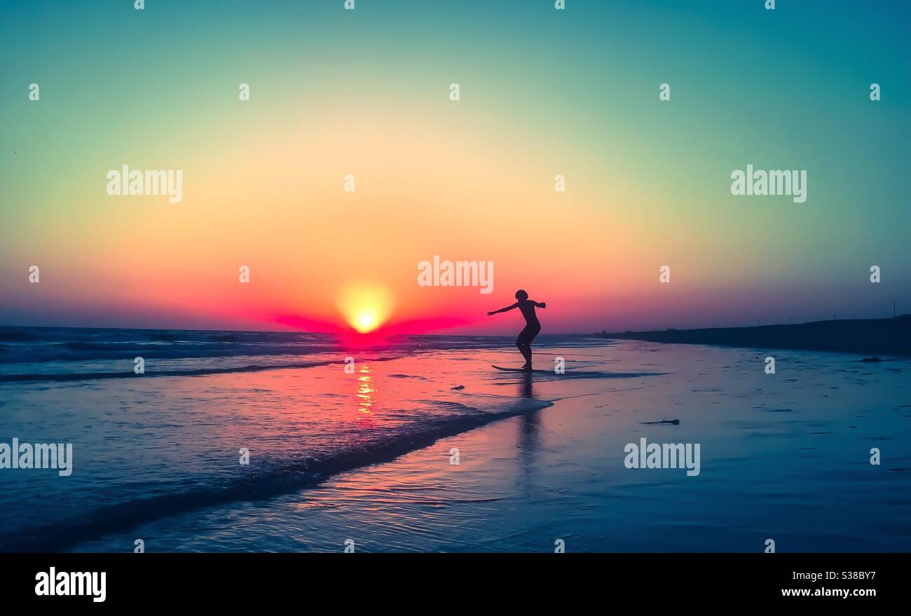 skimboarding silhouette à la plage pendant le coucher du soleil , Banque D'Images